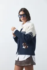 Cardigan de tejido jacquard en color azul marino y blanco, con diseño de conejitos en los laterales, cierre frontal con botones y cuello redondo.