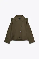 Trench corto color verde militar, con cuello solapa y capucha. Tiene manga larga con trabillas y botón en los puños, bolsillos delanteros y bajo asimétrico. Cierre frontal con botones. El tejido es repelente al agua.