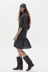 Vestido corto de lino color gris oscuro, con mangas abullonadas, cierre frontal con botones y volado en el ruedo.