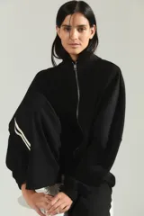 Campera de cuello alto con cierre frontal completo, mangas largas con puños elásticos y diseño holgado.
