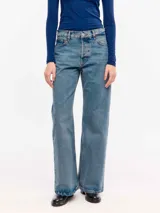 Jean de denim 100% algodón con lavado medio de aspecto vintage, tiro medio y corte flare con perneras ligeramente acampanadas.