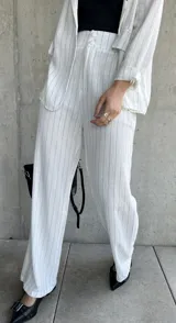 Pantalón blanco con finas rayas verticales negras, de corte palazzo y tiro alto.