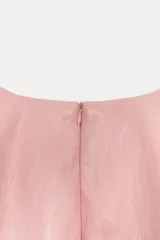 Top de cuello redondo y manga sisa color rosado con acabado efecto piel, de corte entallado en la cintura y pliegues en los hombros.