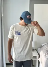 Remera beige de manga corta con estampado gráfico en azul en la espalda que incluye el texto "BROKERS GRAPHIC RESEARCHING" y "THE NEW WAVE BROKERS".