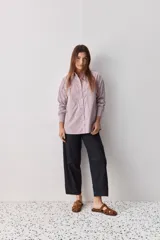 Camisa de calce relajado con diseño a rayas verticales en tonos azul y blanco, cuello clásico, mangas largas con puños abotonados y cierre frontal con botones. Presenta bolsillos aplicados en el delantero y una silueta versátil.