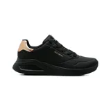 Championes Skechers modelo Uno Lite Shimmer Along, color negro con detalles metalizados en tono oro rosado en el talón y el logotipo lateral. Cuentan con capellada de durabuck sintético con perforaciones sutiles, cordones negros y entresuela de plataforma.