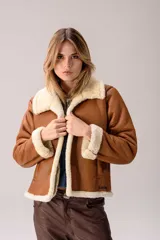 Campera tipo gamulán de cuero color tostado con interior y detalles en piel sintética color crema. Presenta cuello solapa, cierre frontal y mangas largas con puños de piel.