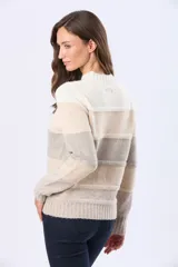 Buzo tejido de punto con diseño de rayas horizontales en tonos gris, rosa, malva y beige. Presenta cuello redondo, mangas largas y puños acanalados, con una pequeña etiqueta de cuero sintético en el ruedo.