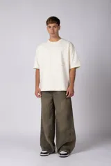 Remera de corte oversize en color crudo, con cuello redondo y mangas cortas. Presenta un pequeño estampado gráfico minimalista en el lado derecho del pecho.