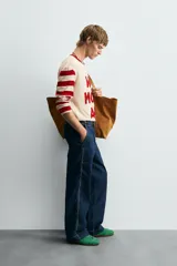 Camiseta de manga larga con cuello redondo, cuerpo color beige claro y mangas a rayas horizontales rojas y beige. Presenta texto frontal en relieve color rojo que dice "WAY MORE ART".