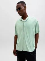 Camisa de manga corta color verde menta, con cuello cubano y cierre frontal con botones.