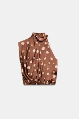 Top de cuello subido y diseño sin mangas, confeccionado en tejido satinado con estampado de manchas abstractas. Presenta drapeado frontal, bajo con elástico y cierre posterior con botones.