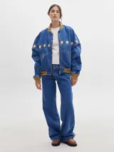 Pantalón jean de tiro alto y corte pinzado, con perneras de caída suelta y levemente anchas en el bajo. Posee pasador con hebilla en la parte trasera.