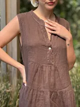 Vestido celeste de lino, sin mangas, con cuello mao y botones de nácar. Presenta varios cortes en su largo, aportando movimiento y un toque moderno a este diseño fresco y elegante.