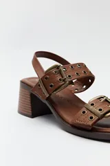 Sandalias negras de cuero sintético con doble tira y hebillas metálicas plateadas. Taco cuadrado bajo y tira trasera con hebilla.