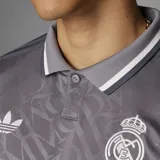 Camiseta de fútbol Adidas del Real Madrid, modelo Tercer Uniforme. Diseño gris con cuello polo, logo de Adidas y escudo del club en blanco. Estampado frontal con el sponsor Emirates Fly Better.