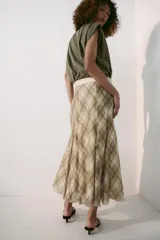 Falda midi de tiro alto, con estampado de cuadros en tonos beige y marrón, costuras marcadas y cierre lateral con cremallera oculta.