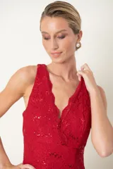 Vestido largo de encaje rojo con brillos, escote cruzado, corte debajo del busto, terminación de blonda y tajo frontal.