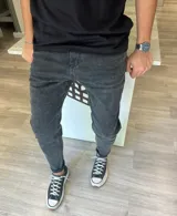 Pantalón de jean skinny color negro con efecto gastado, corte ajustado en las piernas y levemente más holgado en la parte superior.