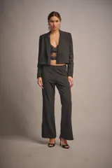 Pantalón de vestir negro con brillo, tiro medio, corte ajustado y ruedo amplio con tajos laterales.