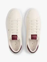 Zapatillas Tommy Hilfiger de diseño bajo color beige, con detalles en tono bordó en el talón y la lengüeta, suela blanca y logo distintivo de la marca en el lateral.