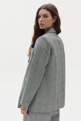 Blazer gris con estampado de cuadros, de doble botonadura, bolsillos delanteros y solapas de muesca. Viene decorado con múltiples pins metálicos en ambas solapas y un pañuelo estampado en el bolsillo del pecho.