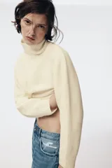 Jersey de punto liso con cuello subido, manga larga y detalle de costura vertical marcada en el frente. Presenta terminaciones en rib en puños, cuello y ruedo.