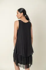 Vestido negro de seda, modelo suelto sin mangas, con escote redondo y volados en el bajo.