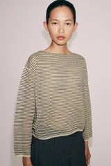 Sweater de punto fino color beige con finas rayas horizontales negras, cuello redondo y manga larga.