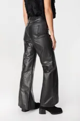 Pantalón de cuero de tiro medio con corte recto y levemente acampanado en el ruedo. Presenta costuras verticales en el centro de la pierna y tajos laterales en la parte inferior.