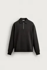 Sudadera polo de corte regular, confeccionada en tejido técnico interlock de algodón con elasticidad. Presenta cuello solapa, cierre frontal de cremallera y manga larga con puños acabados en rib.