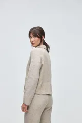 Campera corta con cuerpo de lana tejida en textura tweed y mangas de punto liso en color marrón. Presenta cuello camisero, cierre frontal con botones y bolsillos frontales tipo plaque.