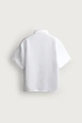 Camisa regular fit confeccionada en tejido de lino, color blanco, con cuello solapa, manga corta y cierre frontal de botonadura.