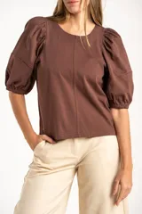 Remera de algodón negro con mangas cortas abullonadas, cuello redondo y costura central frontal.