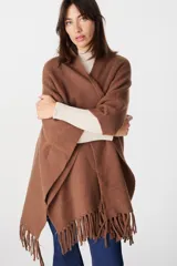 Ruana de tejido suave y envolvente en color blanco, con diseño de corte amplio y terminación de flecos en el ruedo.