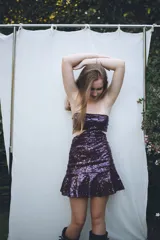 Vestido corto negro con diseño cut-out en la cintura, estilo strapless y ruedo decorado con flecos largos.