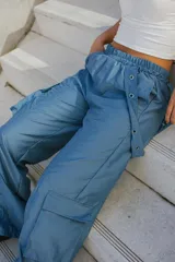 Pantalón estilo cargo parachute de tiro medio, color celeste, con cintura elastizada y bolsillos laterales con solapa.