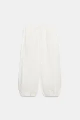 Pantalón confeccionado en mezcla de algodón y poliamida, color blanco, de tiro medio con cintura elástica y cordón ajustable. Posee bolsillos laterales y bajo abullonado con terminación en elástico.