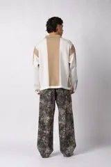 Sweater de punto con diseño a rayas verticales en color beige y blanco, de corte holgado y cuello polo abierto. Presenta un logo bordado en el centro del pecho.