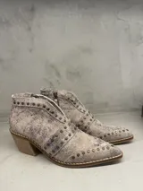 Bota corta de cuero color plata con detalles de tachas, cierre lateral y taco de 5 cm.