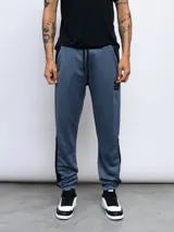 Pantalón de jogging Umbro confeccionado en poliéster, con diseño de bloques de color en azul y negro, cintura elástica con cordón ajustable y puños en los tobillos.