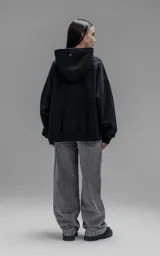 Hoodie oversize de corte crop, color negro, confeccionado en frisa gamuzada de algodón. Presenta capucha forrada, mangas largas con puños elásticos y bolsillo tipo canguro frontal.