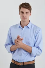 Camisa celeste de vestir, de manga larga, con cuello clásico y bolsillo en el pecho.