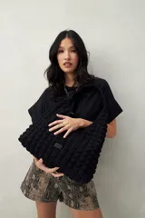 Cartera marrón con textura acolchada y efecto tridimensional. Diseño blando con asa fruncida.