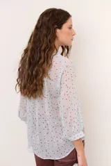 Blusa marrón semitransparente con estampado de lunares celestes, mangas largas abuchonadas, cuello en V con lazos y detalles de volados frontales.