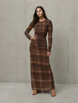 Vestido largo marrón con estampado a cuadros, de manga larga, cuello redondo y diseño ajustado con fruncidos en la cintura.