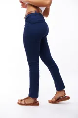 Pantalón azul marino de corte skinny, con bolsillos laterales y traseros. Se ajusta a la cintura con cinturón de cuero marrón.