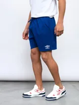 Bermuda deportiva azul rey de felpa, con cintura elástica y cordón de ajuste. Presenta el logo Umbro en blanco en la pierna izquierda.