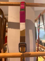 Cinturón de cuero combinado con aguayo tejido y detalles de cuero vacuno en diferentes tonos, con hebilla metálica rectangular.