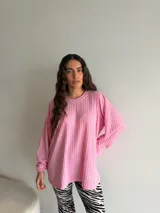 Buzo de viscosa y poliéster color rosado, con textura acanalada, cuello redondo y mangas largas holgadas.